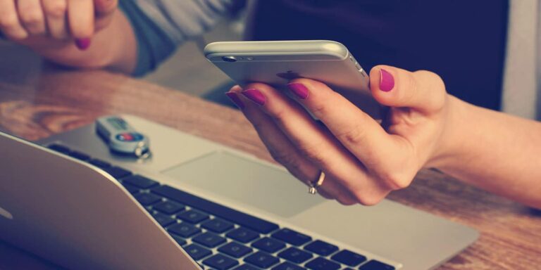 Personne consultant un devis d’électricien sur smartphone et ordinateur portable, estimation du coût des travaux électriques